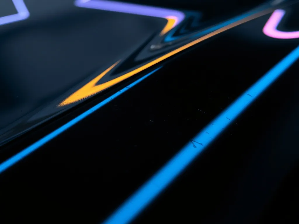 Close up of a black car paint surface reflecting a neon ligh